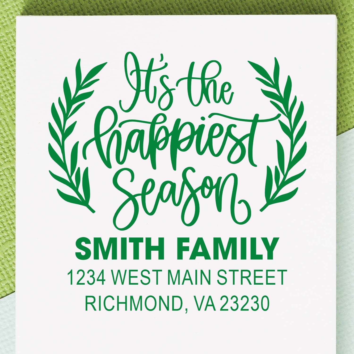 Personalized holiday rubber stamp with Its the happiest season, laurel leaves, Smith Family name, and custom address.