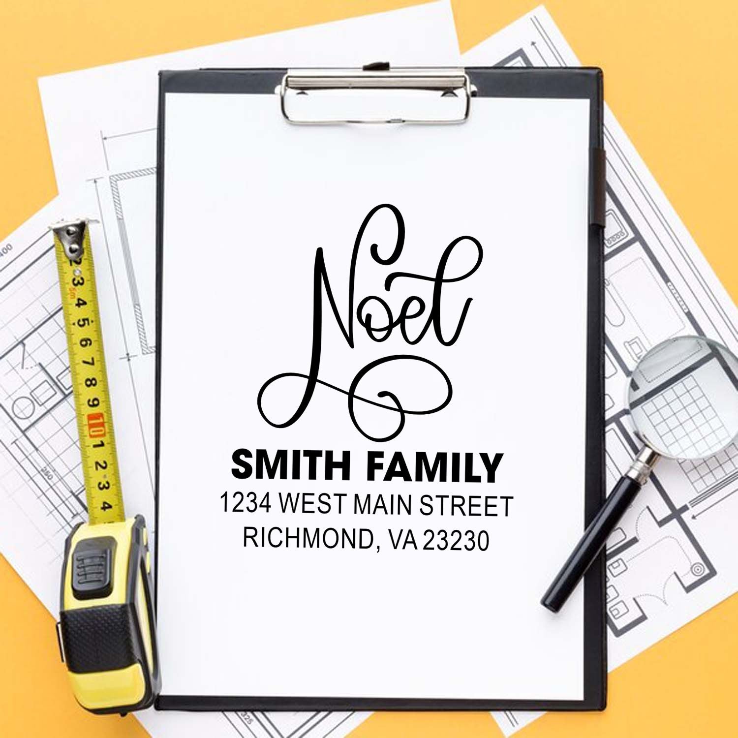 Personalized return address rubber stamp for Noel Smith Family, shown on a clipboard with house plans.