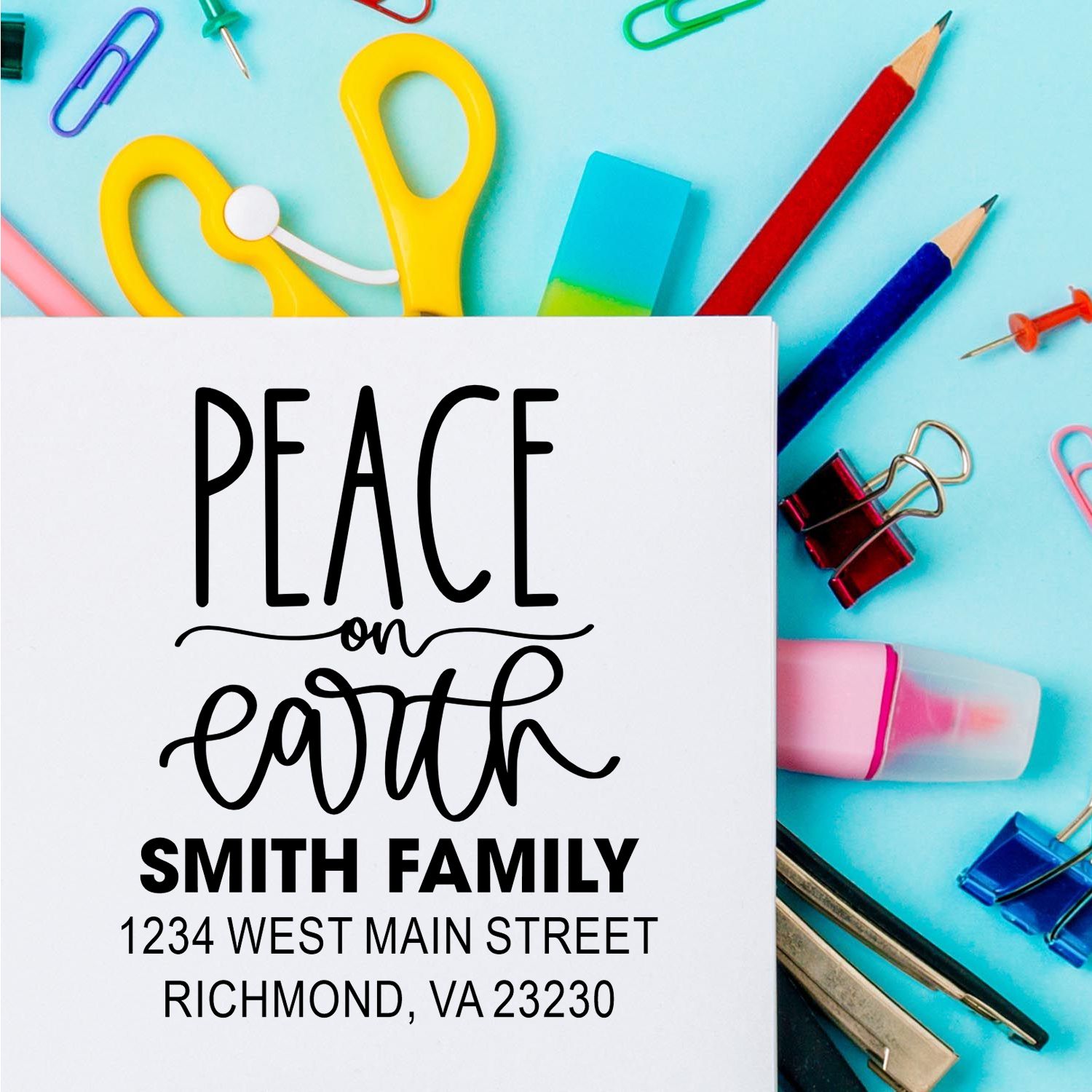 Custom holiday address rubber stamp design reading Peace on Earth, Smith Family, with colorful stationery and office supplies.