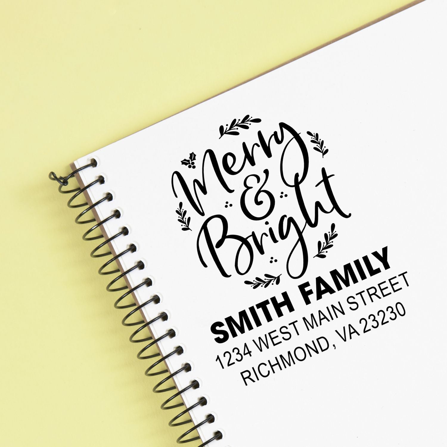 Personalized Merry & Bright custom rubber stamp with Smith family address on white spiral notebook.