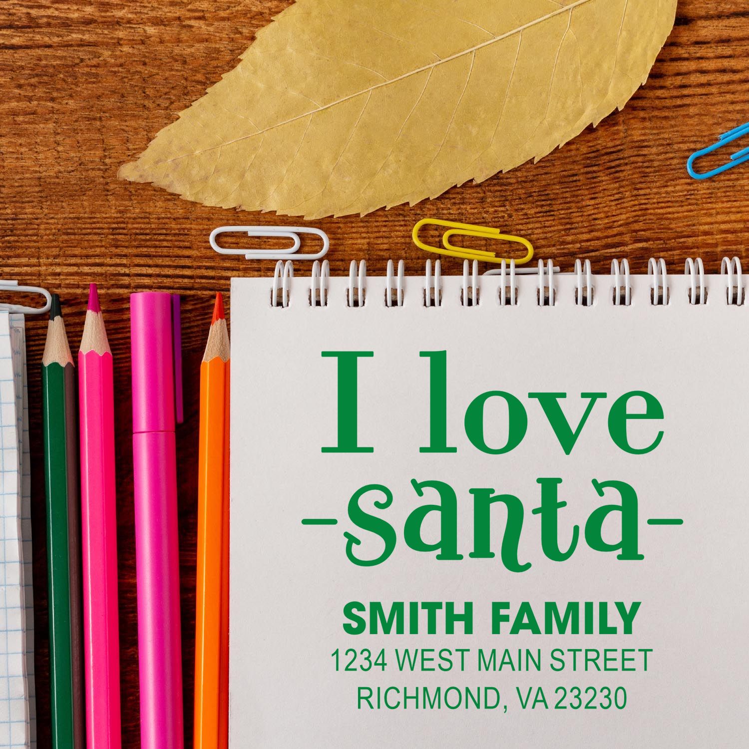 Personalized Christmas address rubber stamp reading I Love Santa with Smith family address on a notebook.
