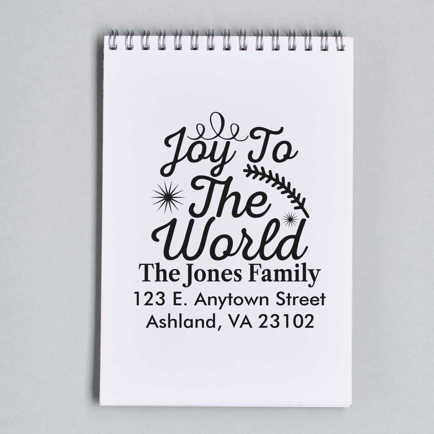 Personalized Joy To The World Christmas return address rubber stamp on a notepad mockup.