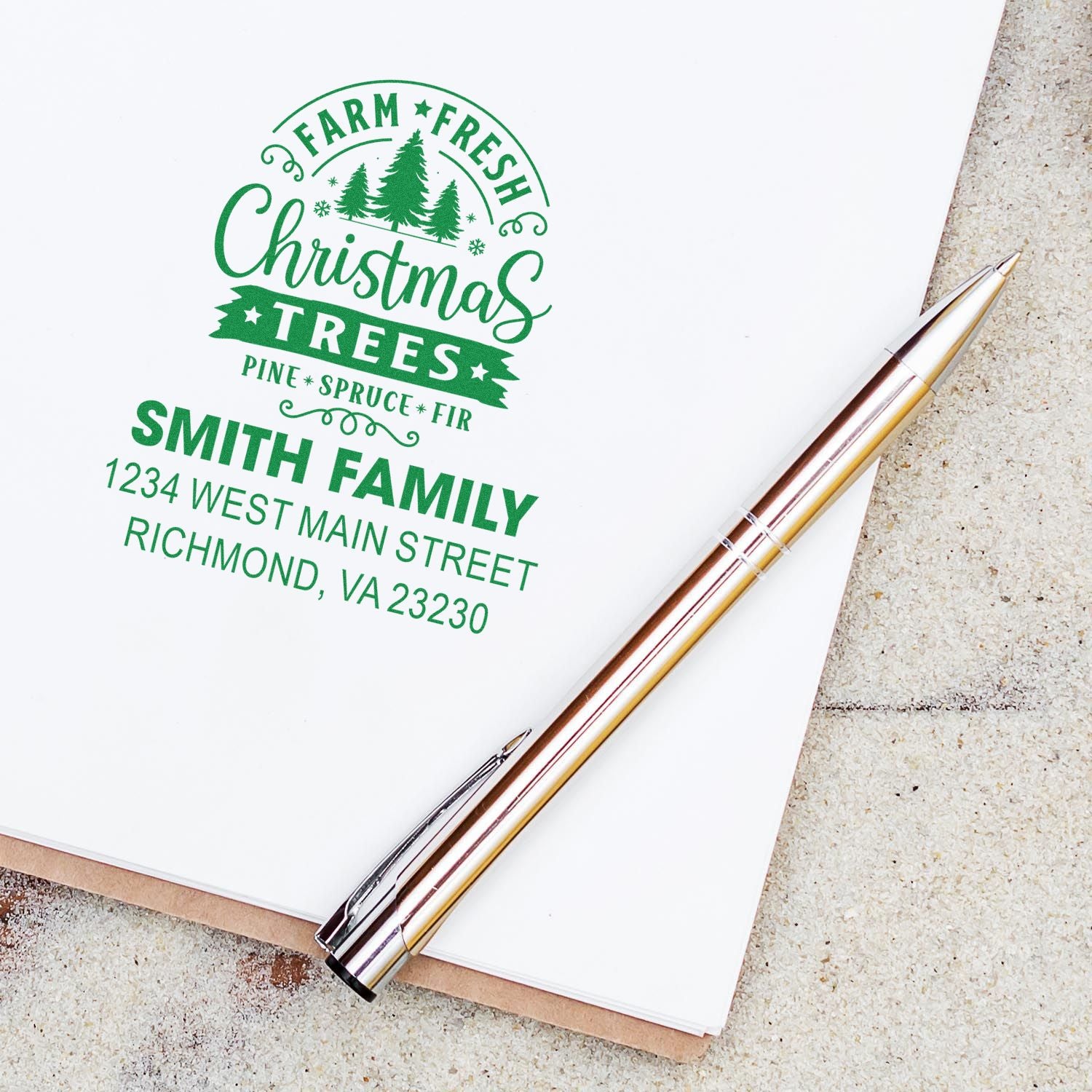 Personalized Christmas tree farm rubber stamp with Smith family return address on white paper and pen