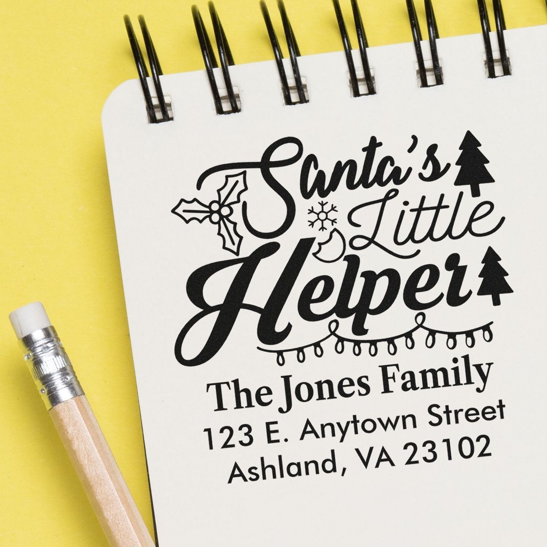 Custom Santas Little Helper holiday rubber stamp with family name and address on a notebook.