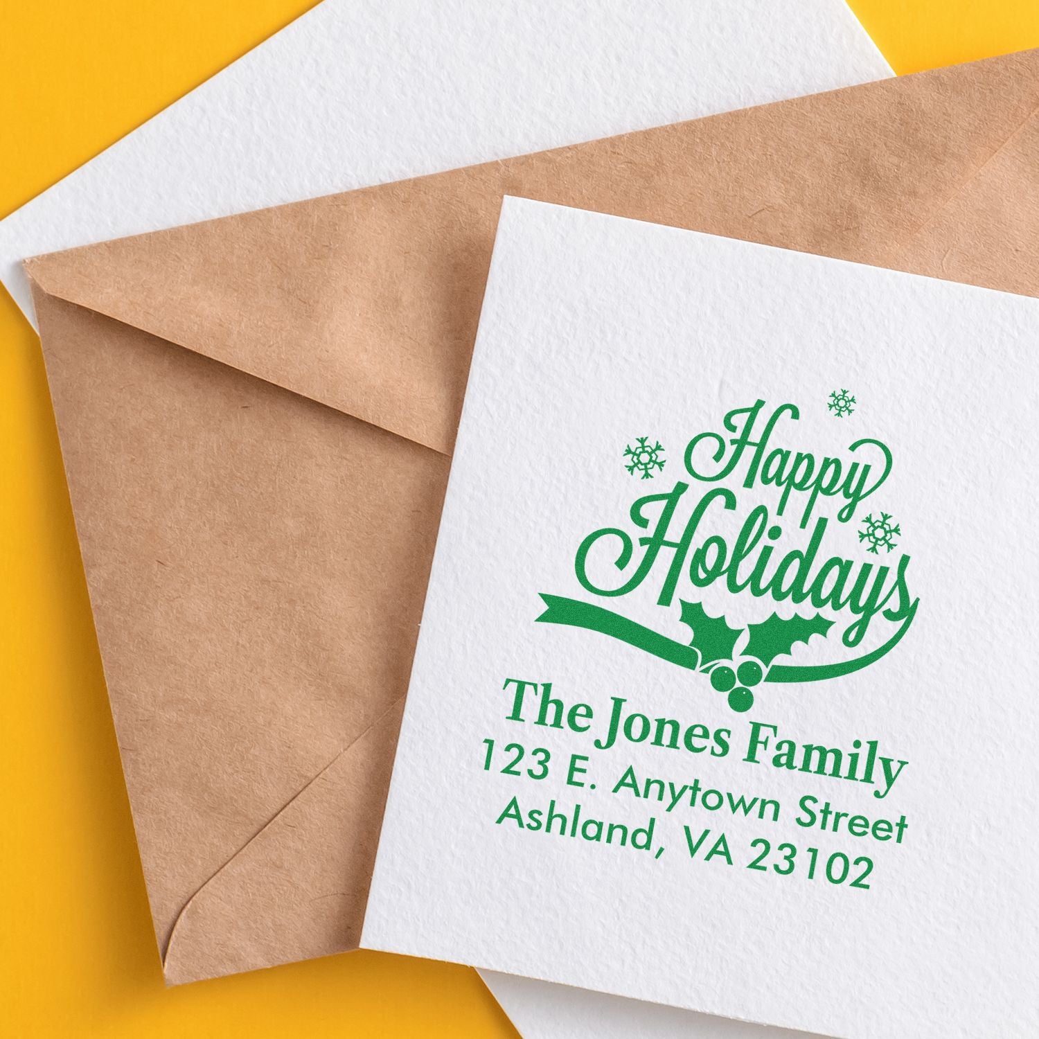 Personalized holiday address rubber stamp on greeting card and kraft envelope, featuring green Happy Holidays design.