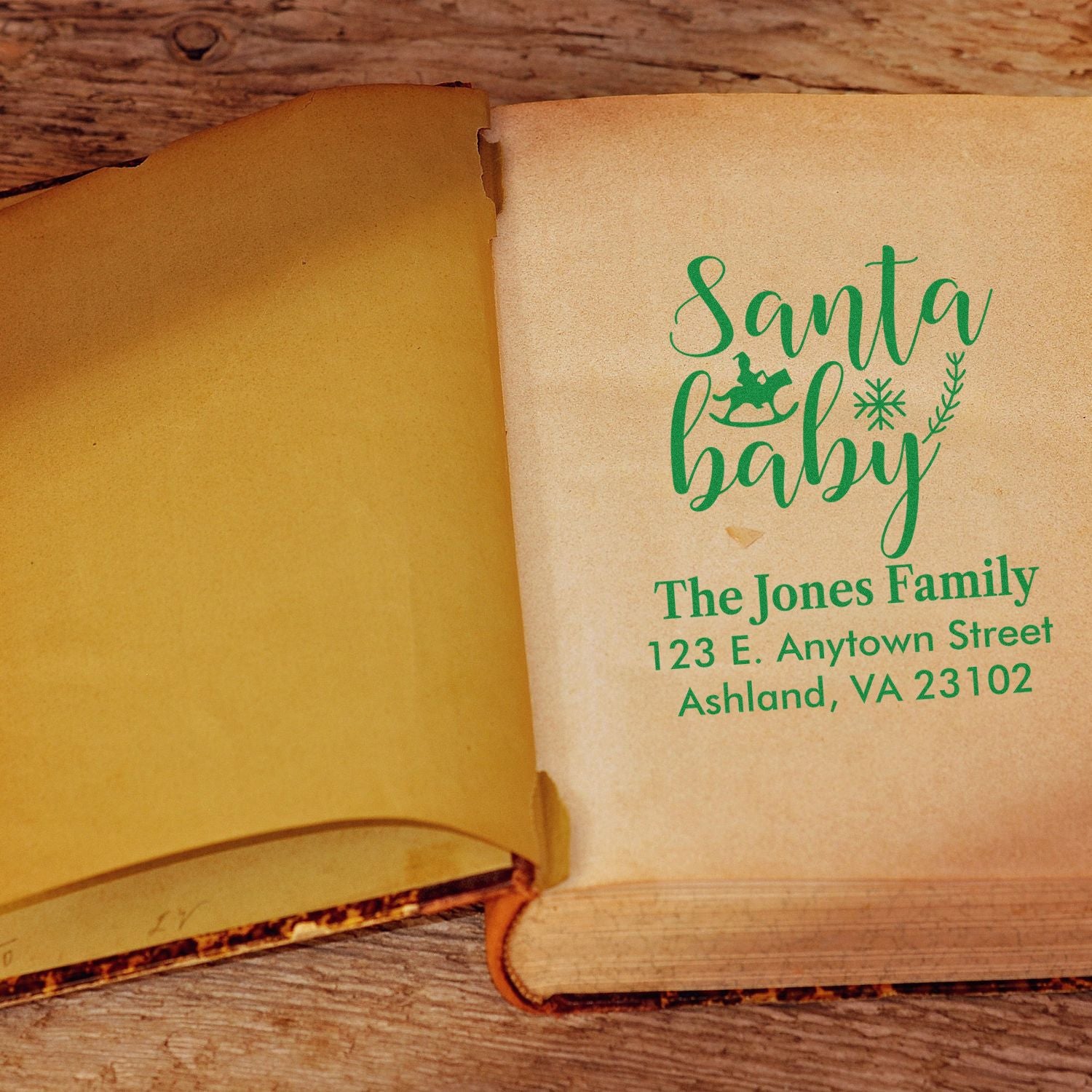 Custom Santa Baby return address rubber stamp on book page for holiday cards and Christmas mailings.
