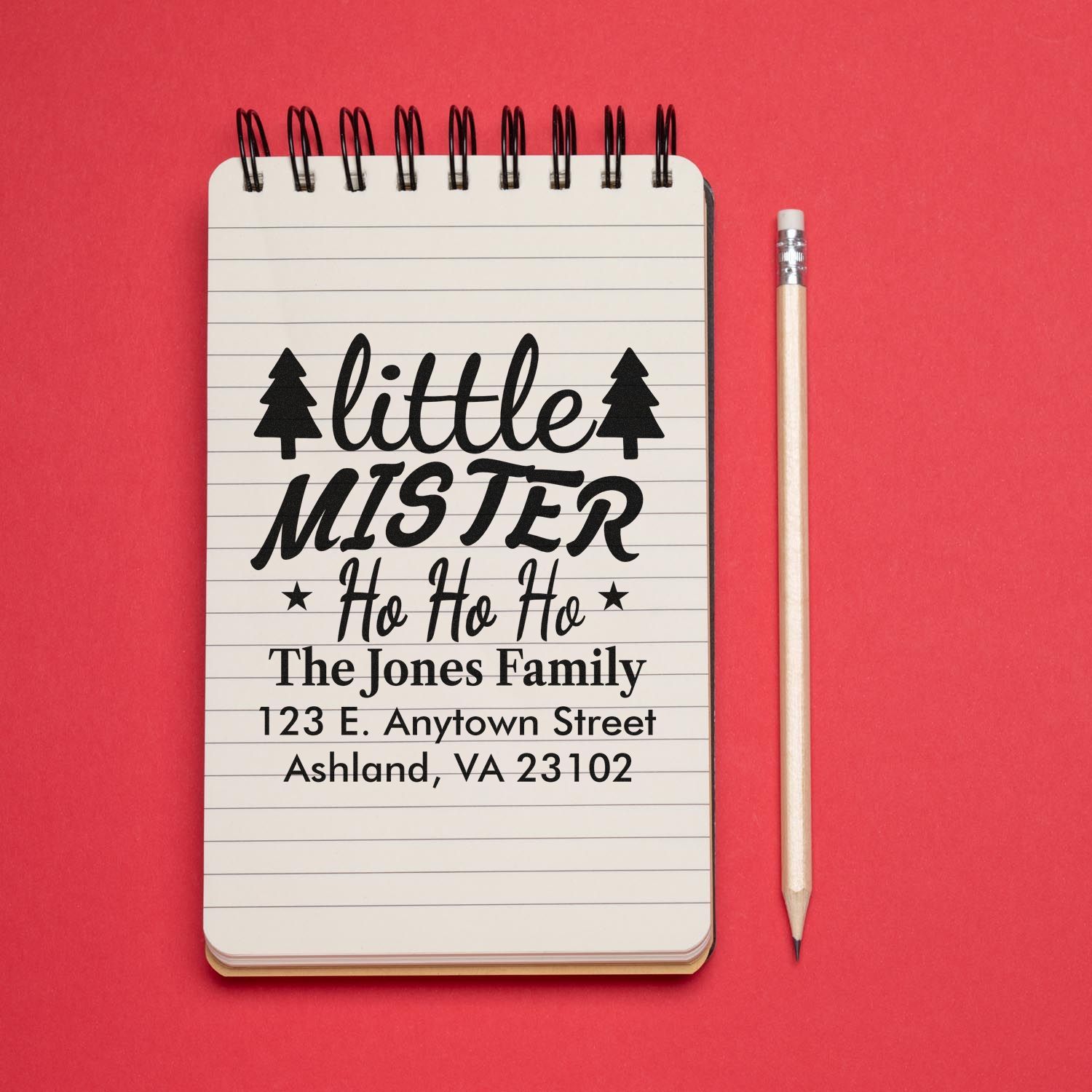 Custom rubber stamp proof for Little Mister Ho Ho Ho, with family name and address on notebook mockup.