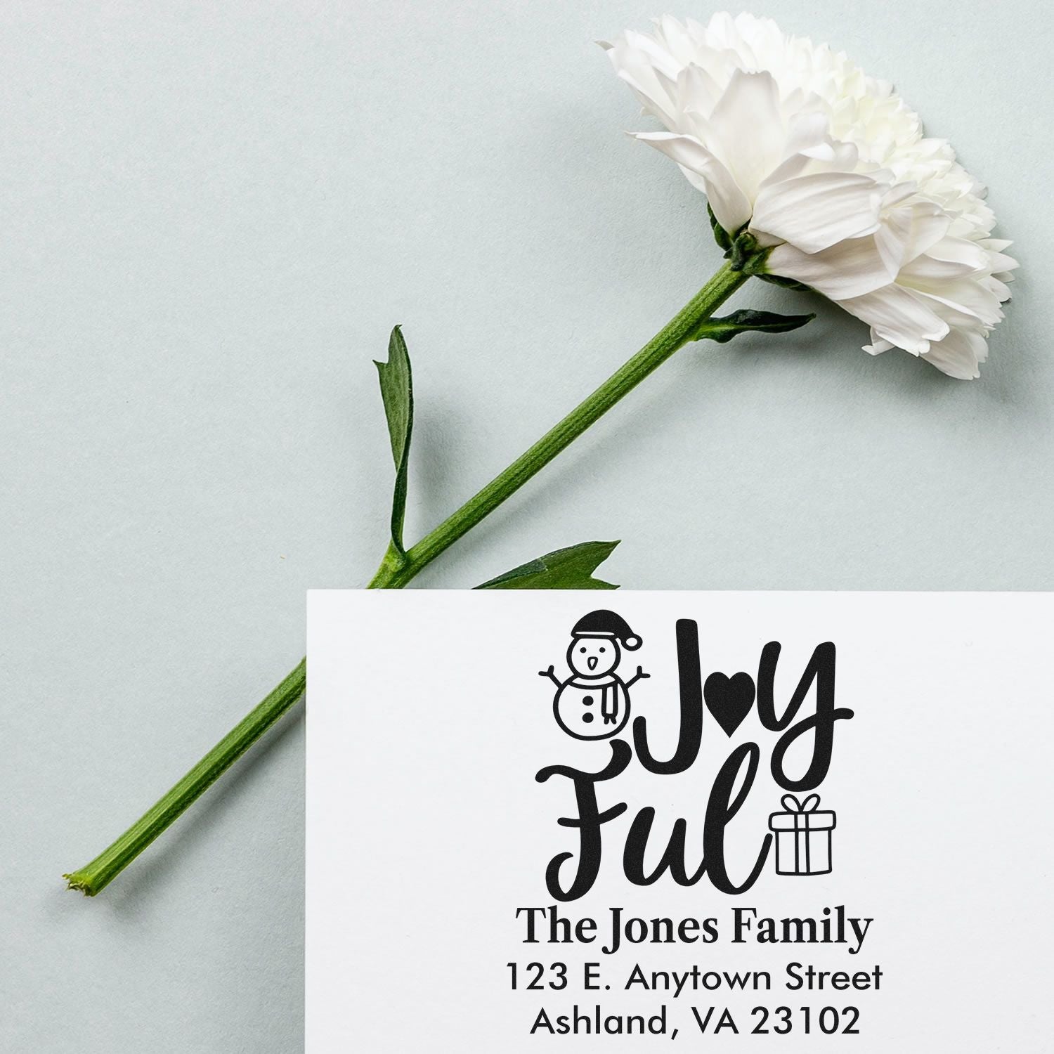 Custom holiday rubber stamp with Joyful design, snowman and gift icons, plus personalized return address for The Jones Family