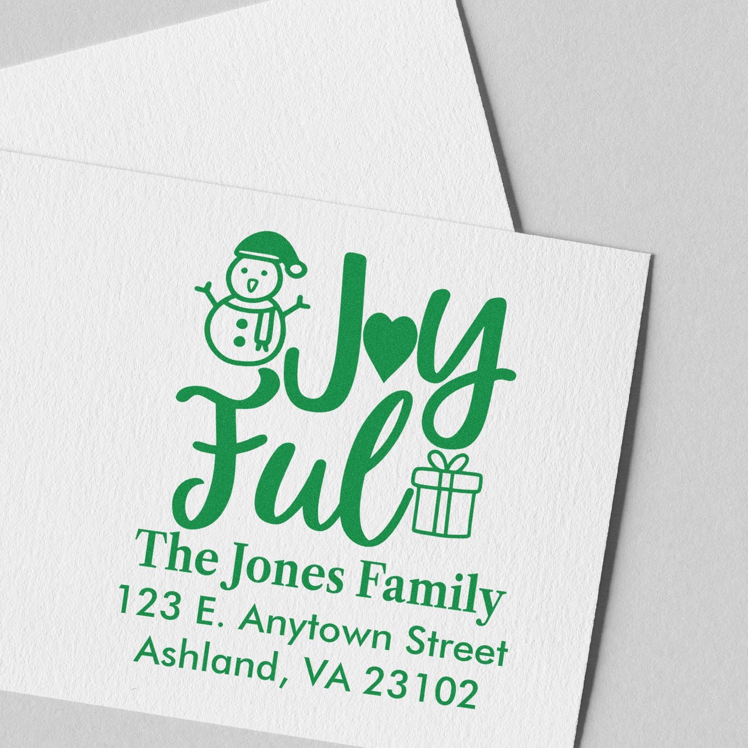 Personalized holiday rubber stamp with Joy Full snowman and gift design, family name, and return address for Christmas cards.