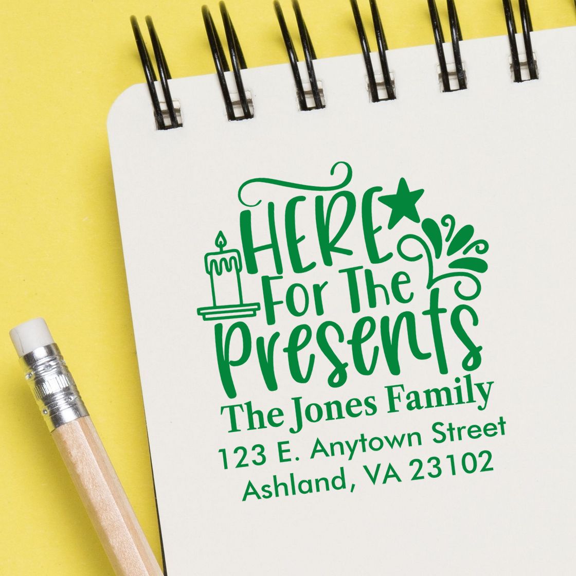 Custom holiday rubber stamp design with Here for the Presents and return address for The Jones Family on a notebook mockup.