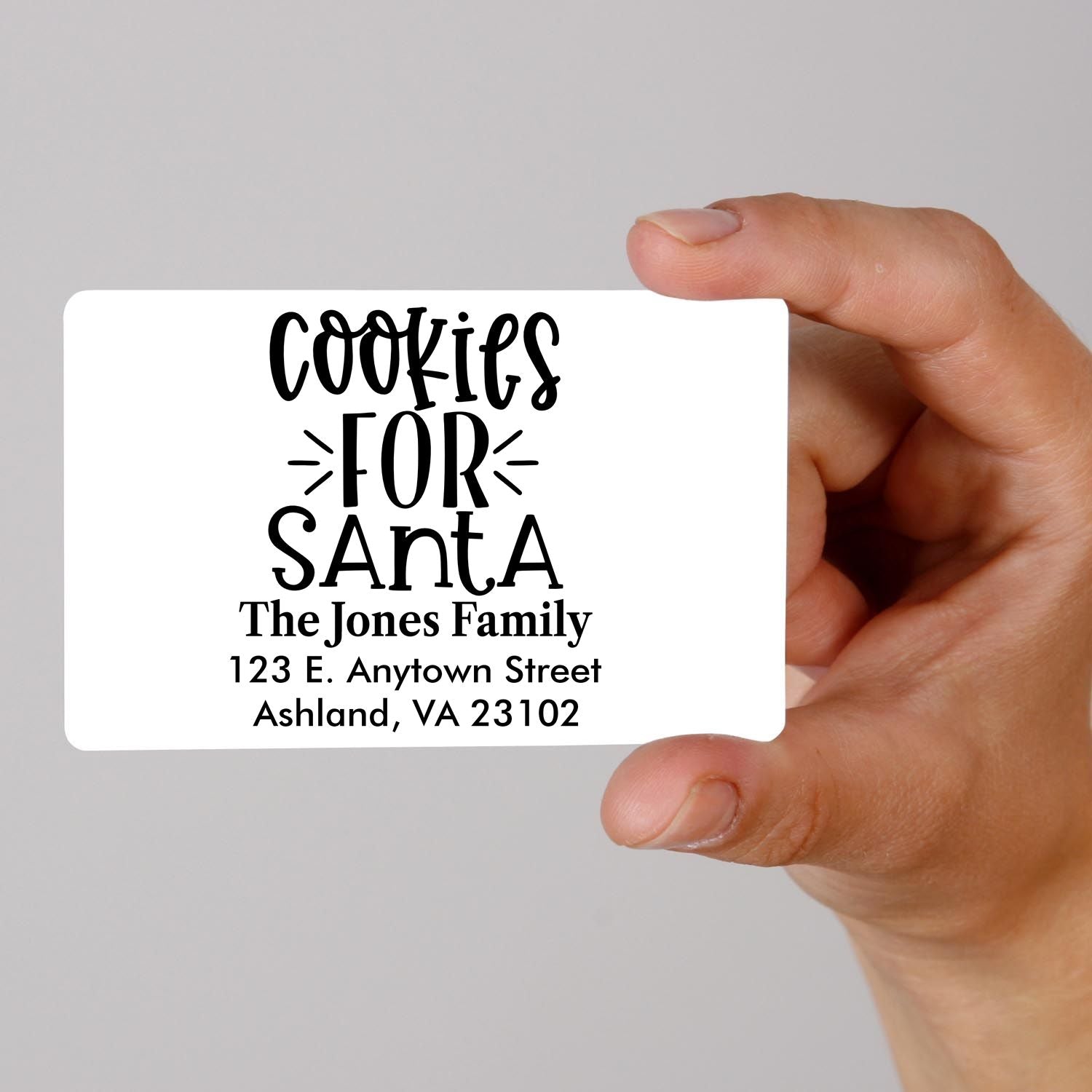 Hand holding custom rubber stamp design for Christmas cookies for Santa with family name and return address.