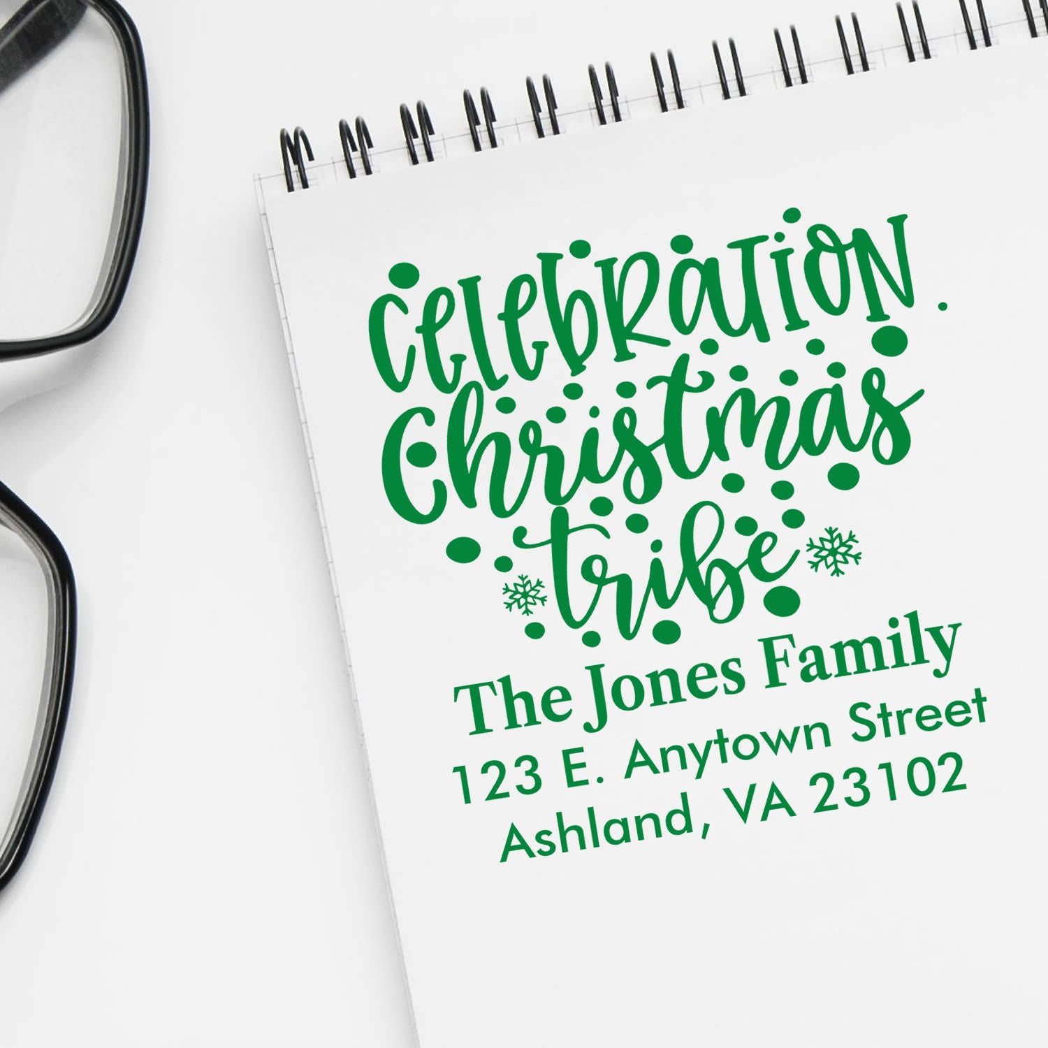 Custom Christmas family return address rubber stamp with festive green lettering and address on notebook