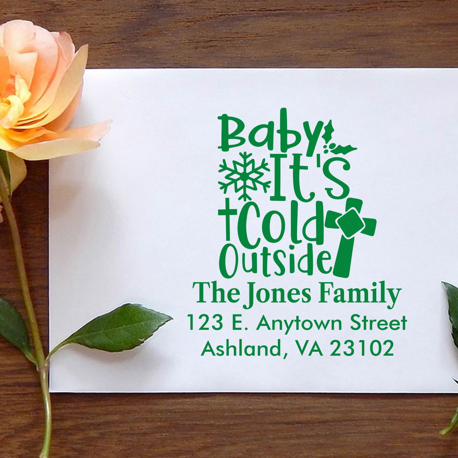Personalized holiday return address rubber stamp with Baby, Its Cold Outside design in green ink on a white envelope.