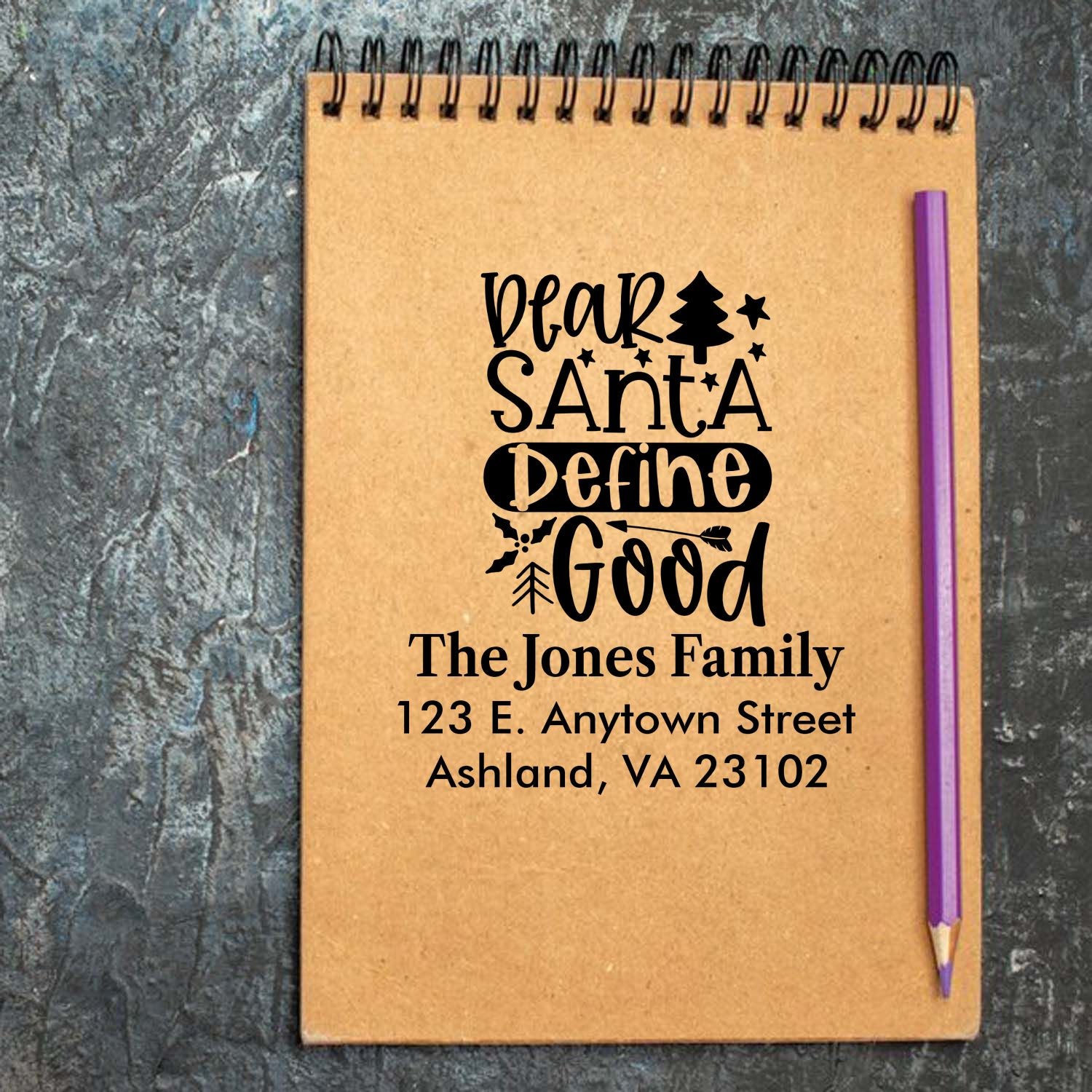 Custom Christmas rubber stamp on a notebook with Dear Santa Define Good design, personalized family name and return address.