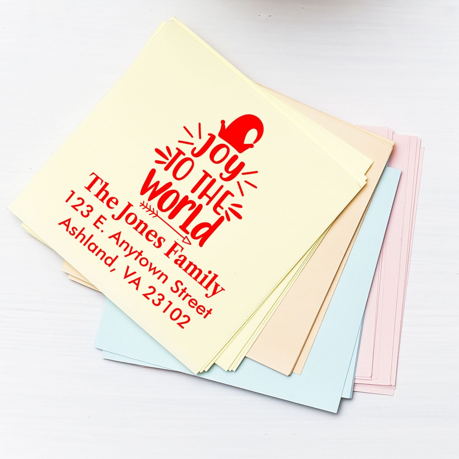 Custom Christmas address rubber stamp on pastel cards, with Joy to the World for festive family mailings.