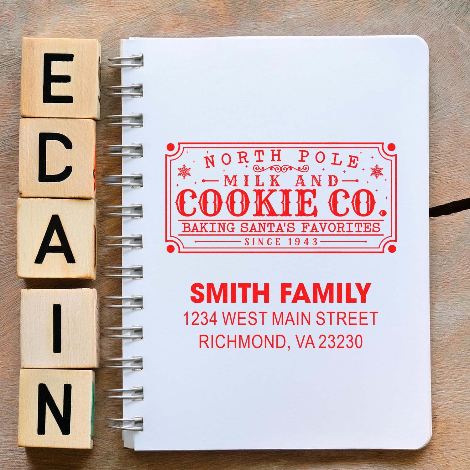 Custom holiday address rubber stamp mockup for North Pole Milk and Cookie Co., with Smith Family return address on a notebook.