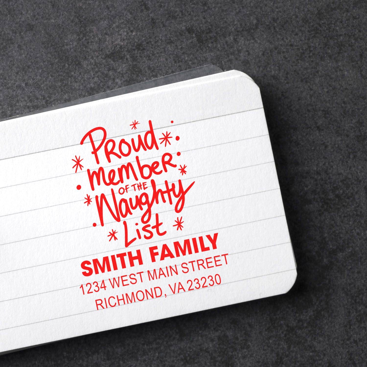 Personalized holiday rubber stamp reading Proud member of the naughty list with family name and address for Christmas mail.
