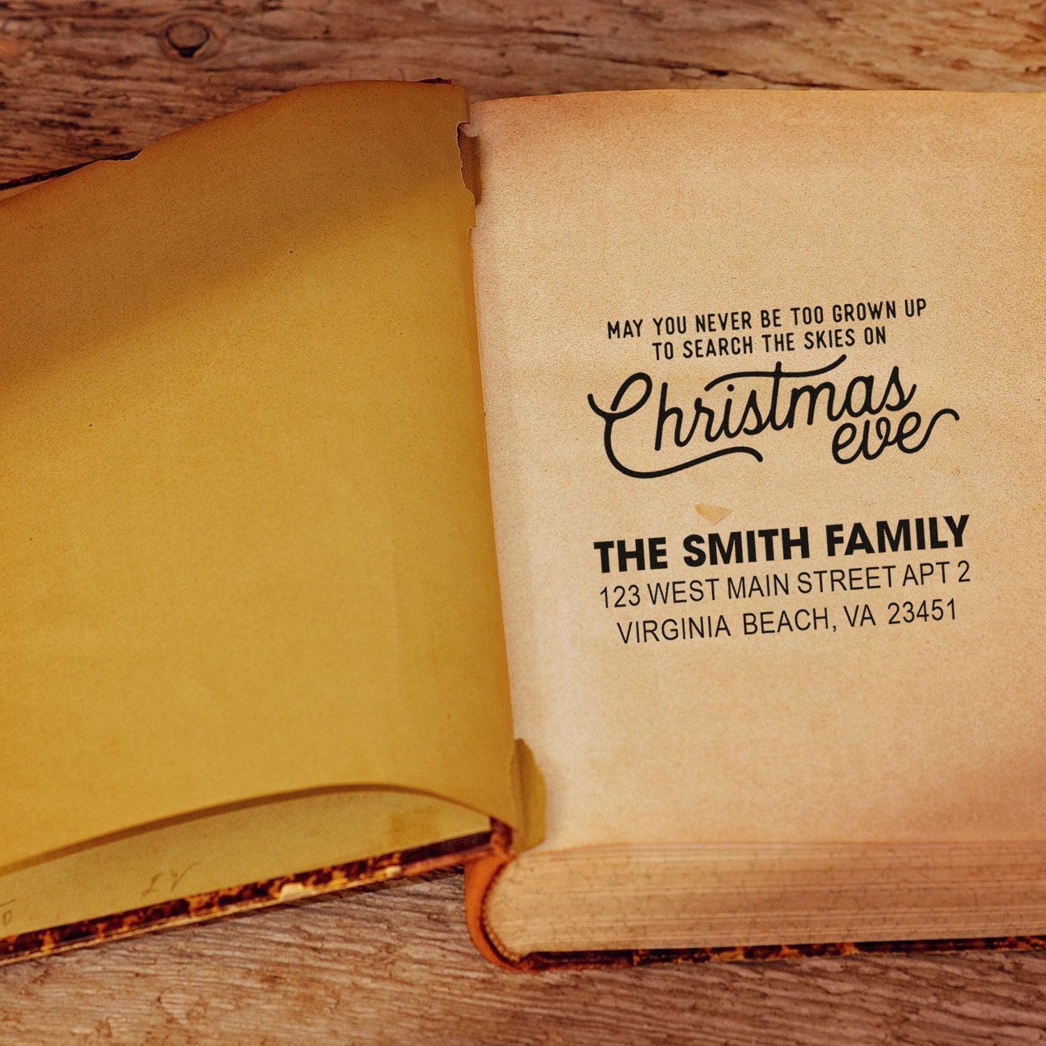 Custom Christmas Eve rubber stamp with family name and address on an open book page.