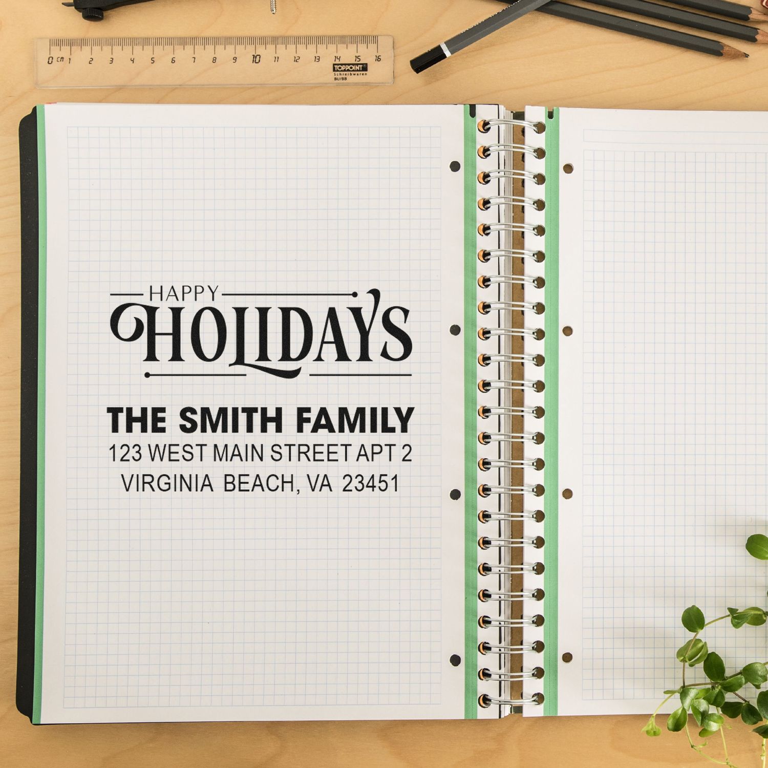 Custom holiday rubber stamp with Happy Holidays and family address imprint in an open planner notebook.