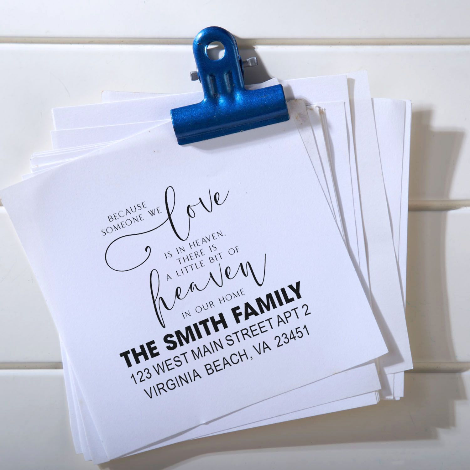 Custom rubber stamp sample on folded stationery with memorial quote, family name, and return address.