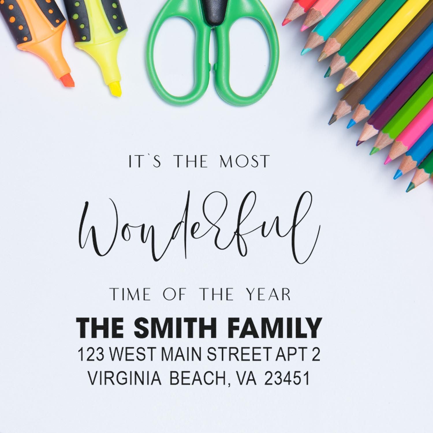 Personalized address rubber stamp with holiday message for card making, shown with colored pencils and scissors.