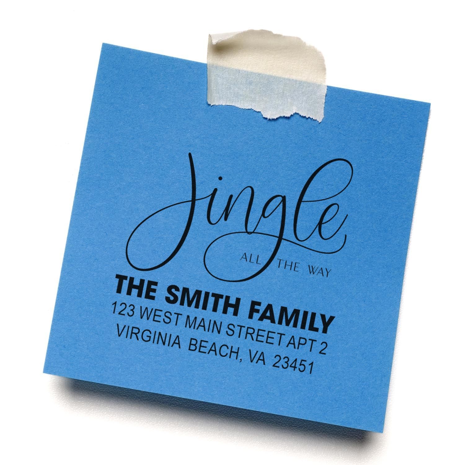 Custom holiday return address rubber stamp on blue paper, featuring Jingle all the way and family name mailing details.