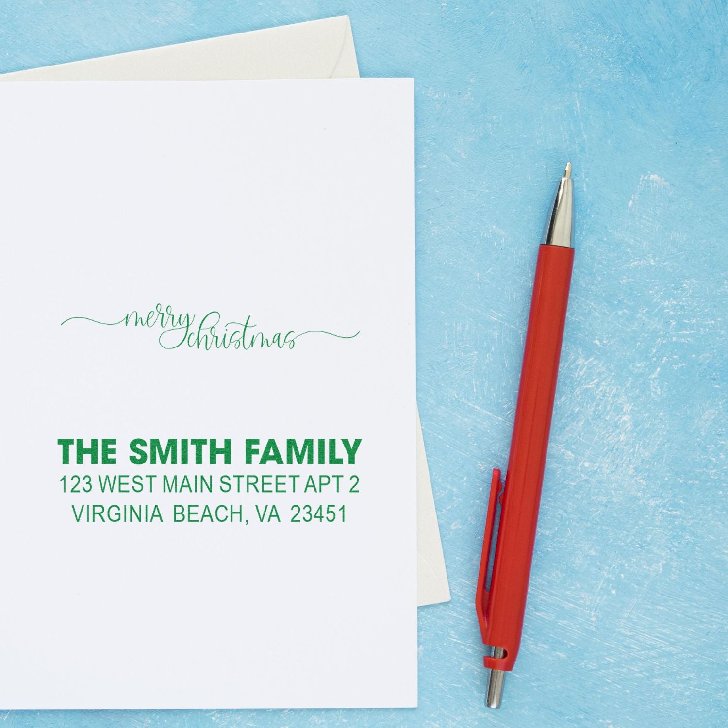 Personalized Christmas return address rubber stamp on holiday card with custom family name and address.