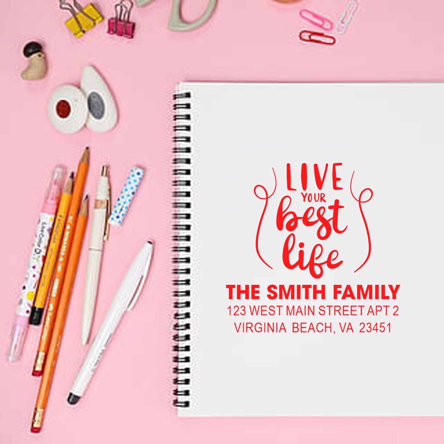 Custom rubber stamp with Live your best life and family name address, shown on a notebook for personalized stationery.