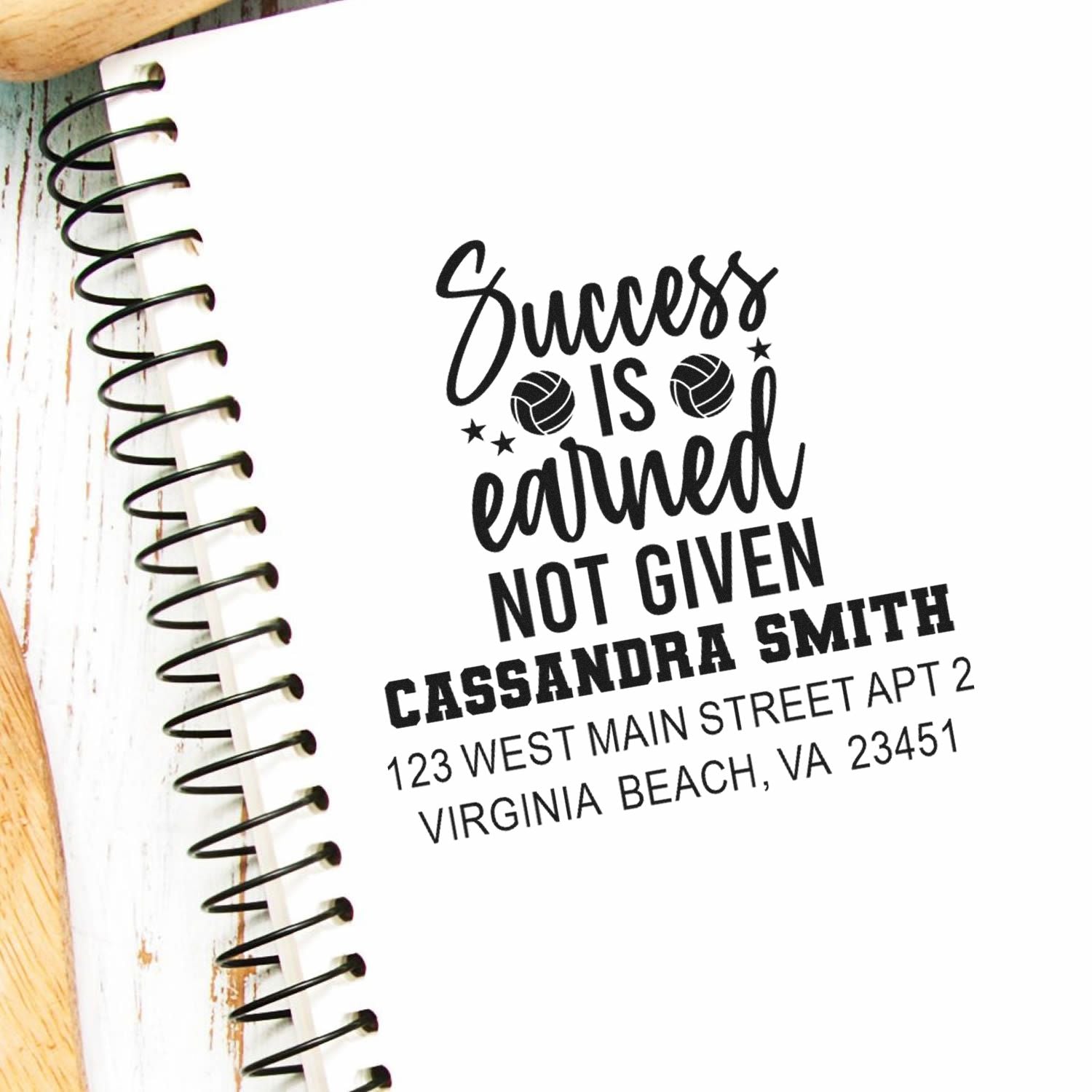 Personalized rubber stamp with Success is earned not given message and name/address imprint on notebook page.