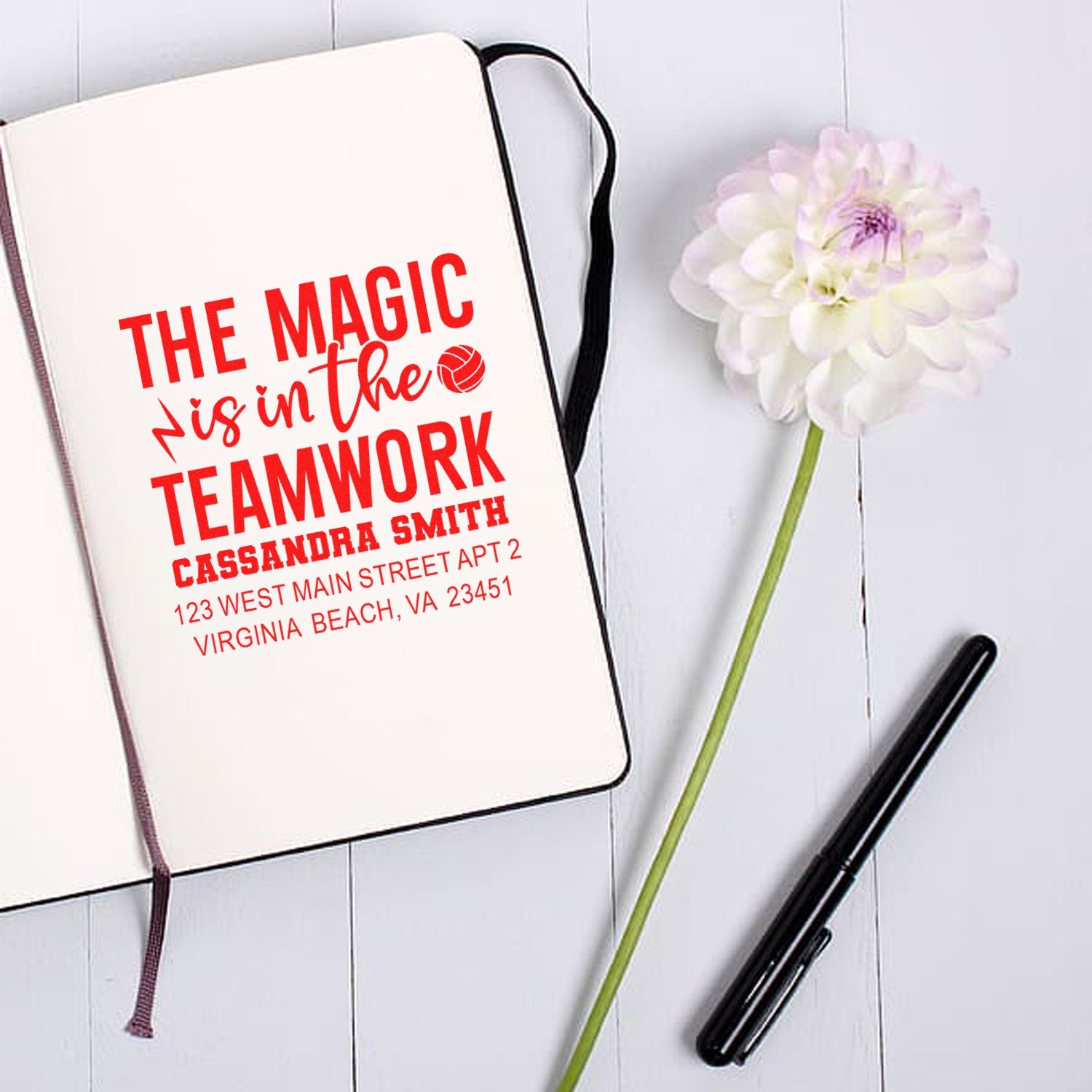 Custom rubber stamp on notebook featuring The Magic is in the Teamwork motivational name and address design.
