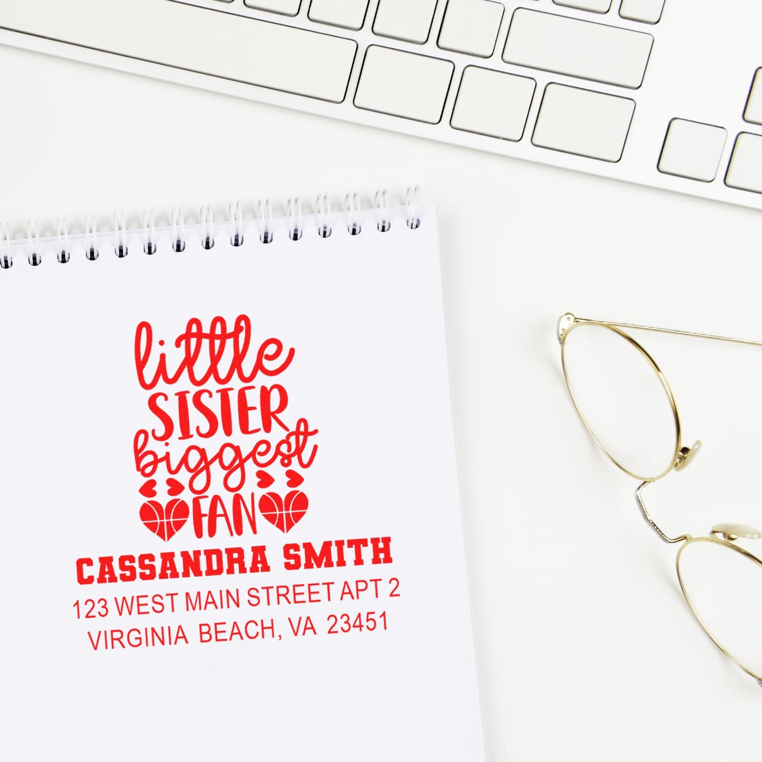 Custom rubber stamp design reading little sister biggest fan with name and address on a notebook page.