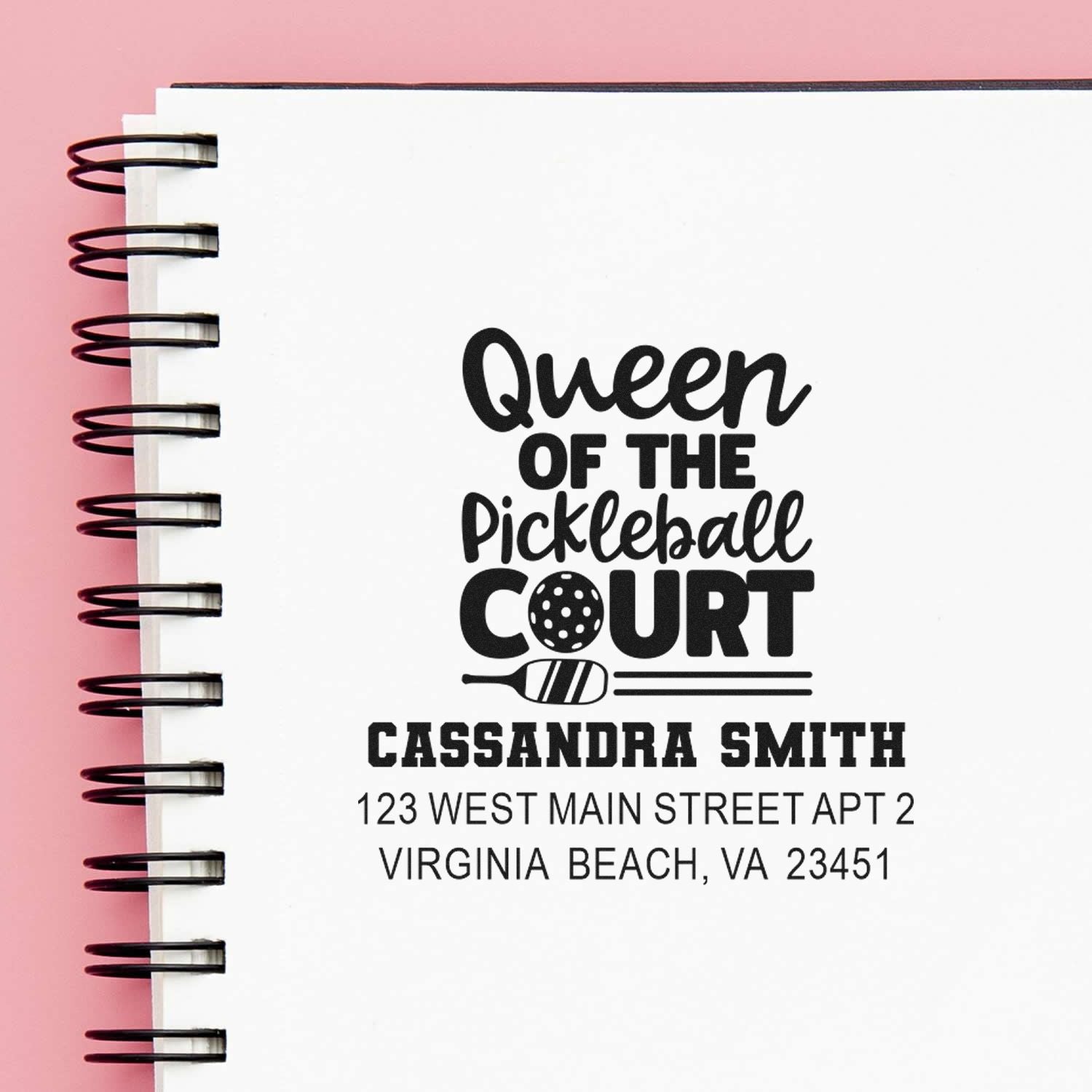 Custom rubber stamp design reading Queen of the Pickleball Court with personalized name and address on a notebook page.