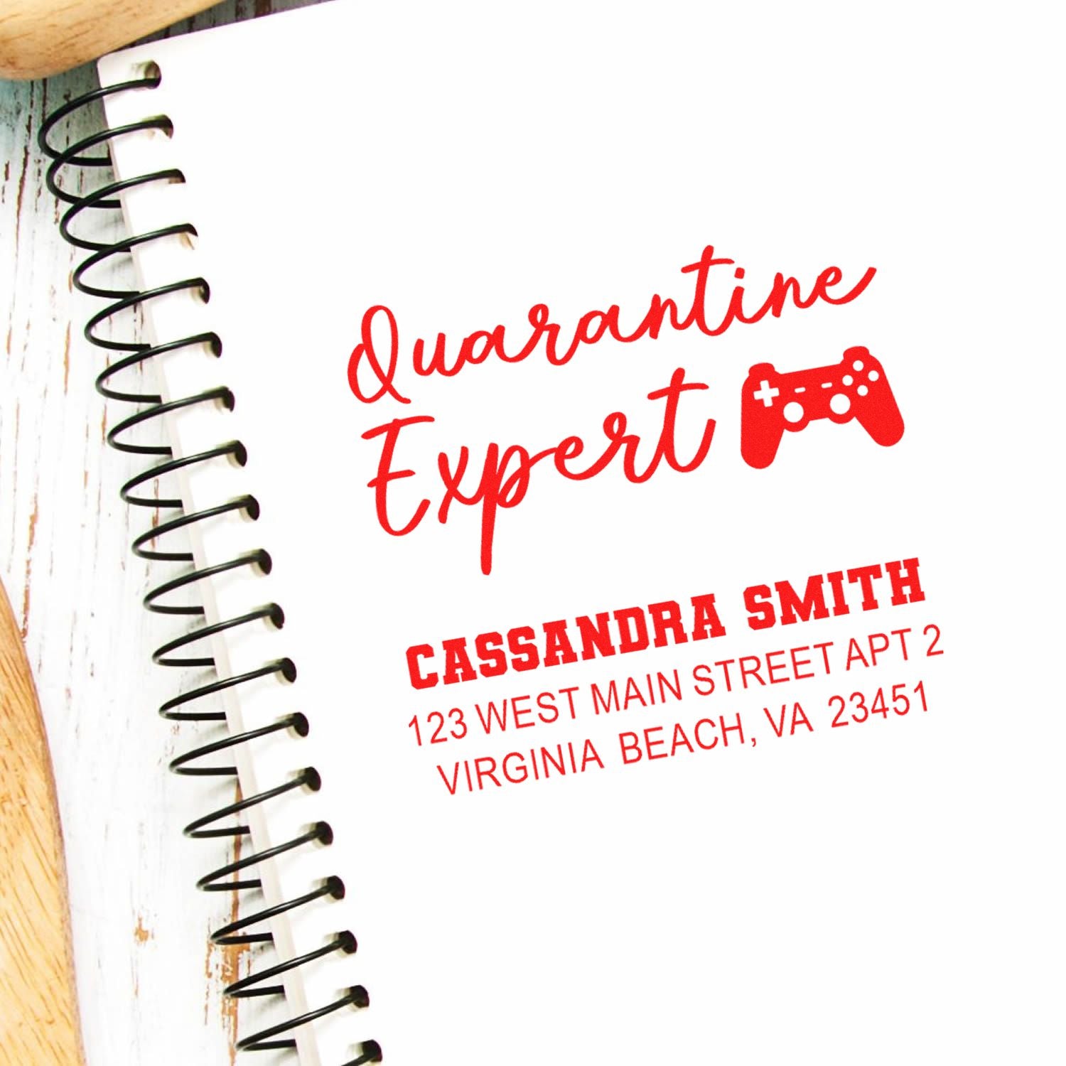 Custom rubber stamp design reading Quarantine Expert with game controller icon and personalized name and address on a notebook.