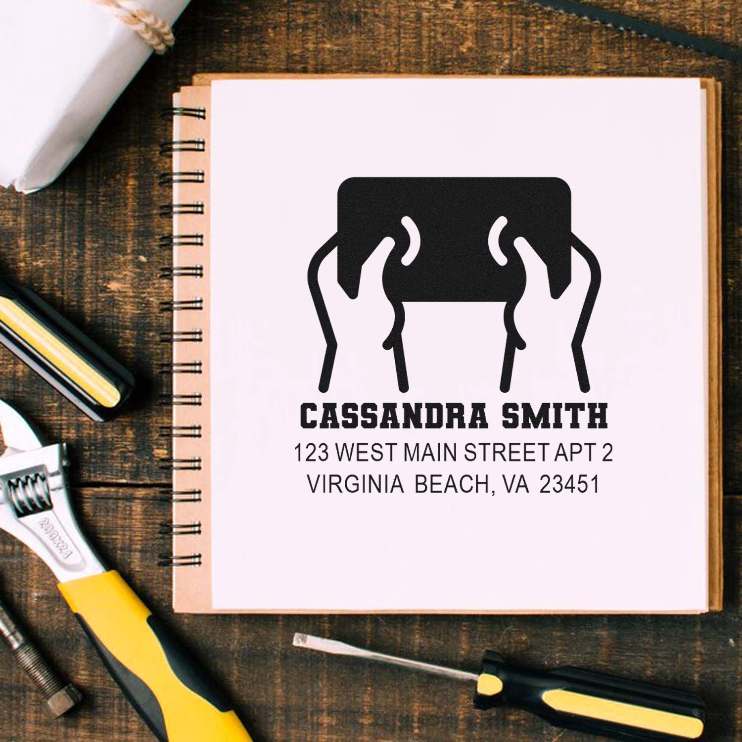 Personalized rubber address stamp for Cassandra Smith with mailing address, shown on a notebook.