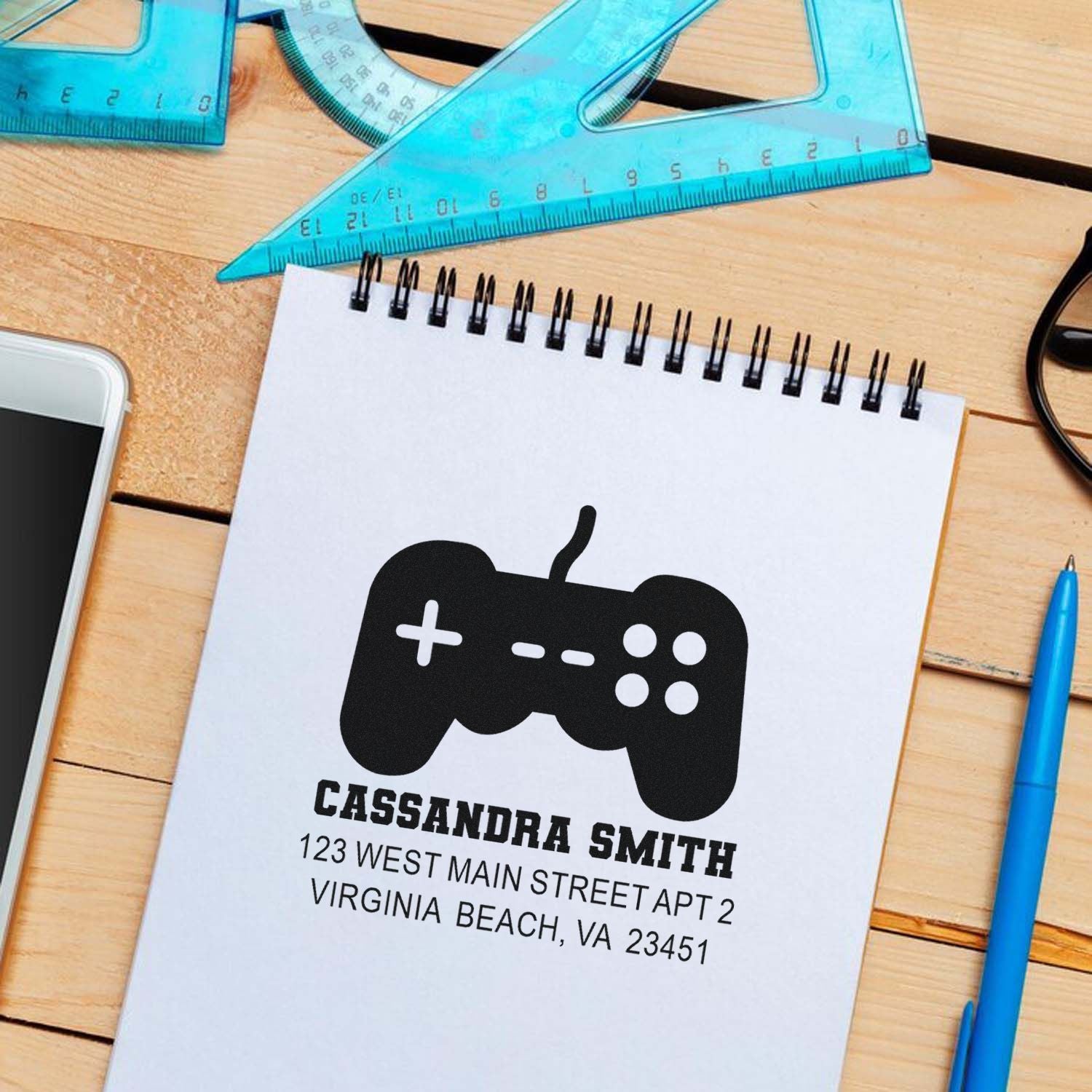 Custom return address rubber stamp with game controller icon, name, and address for gamer mail labeling.