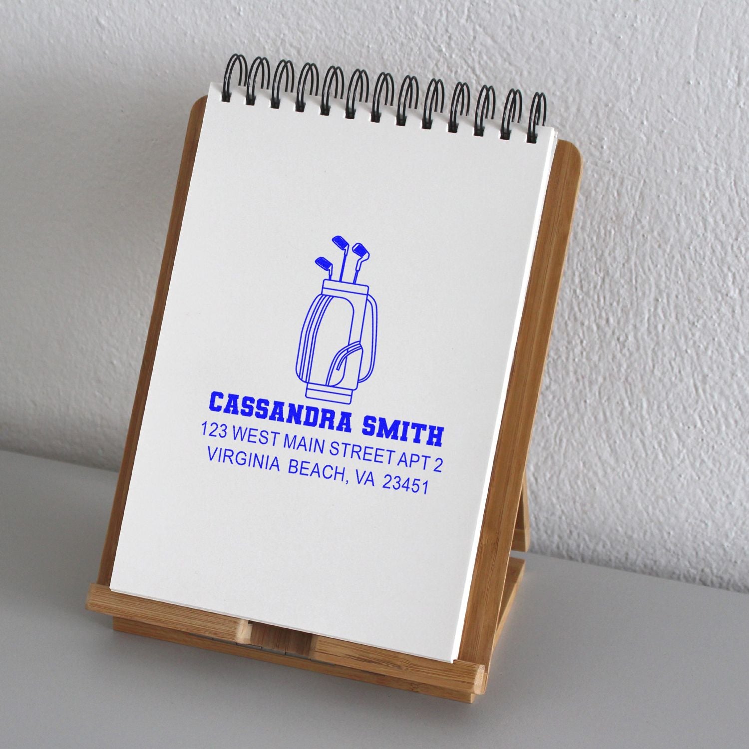 Personalized return address rubber stamp with golf bag design, stamped on a notepad for custom mailing stationery.