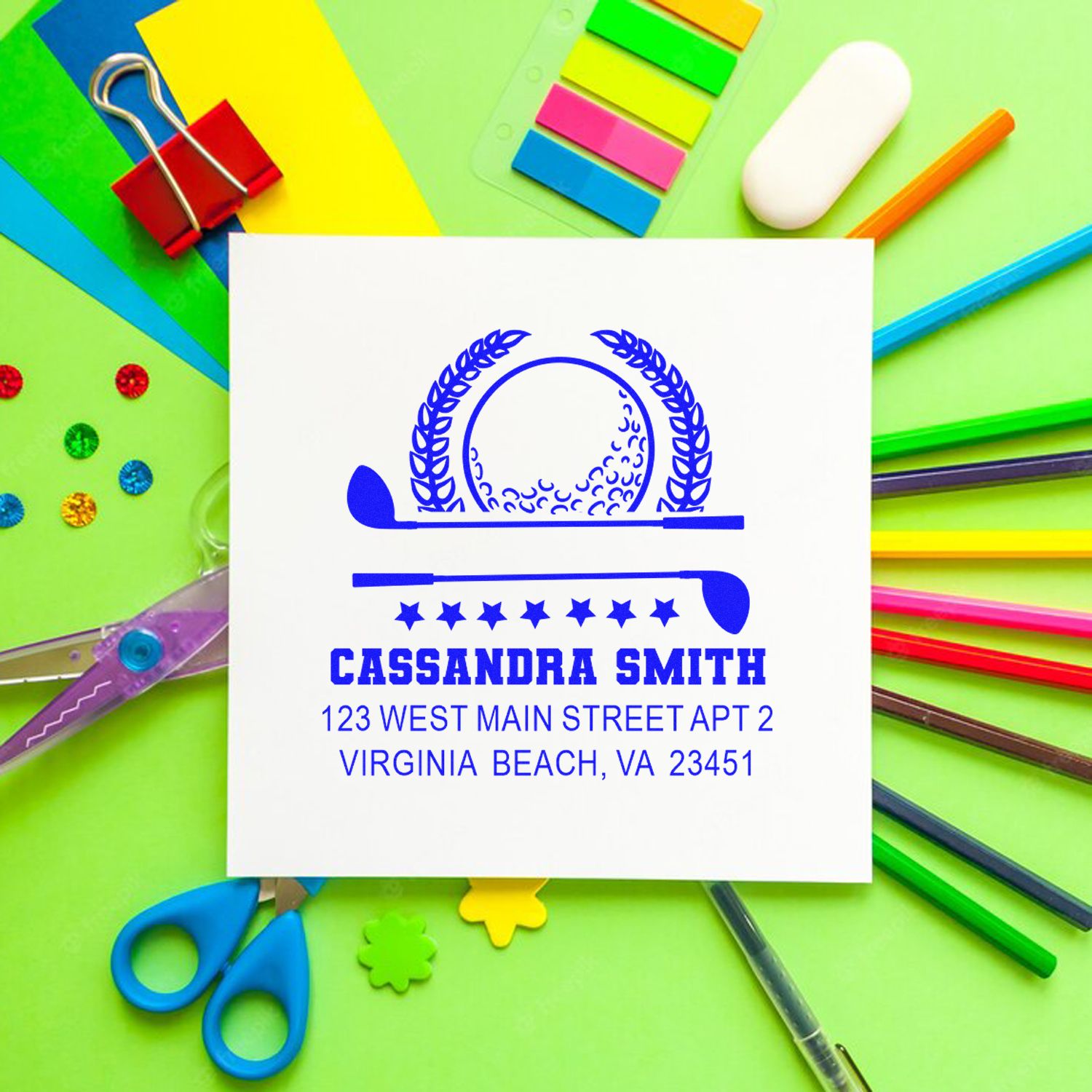 Custom rubber address stamp impression with name and address, shown on paper with colorful stationery and school supplies.