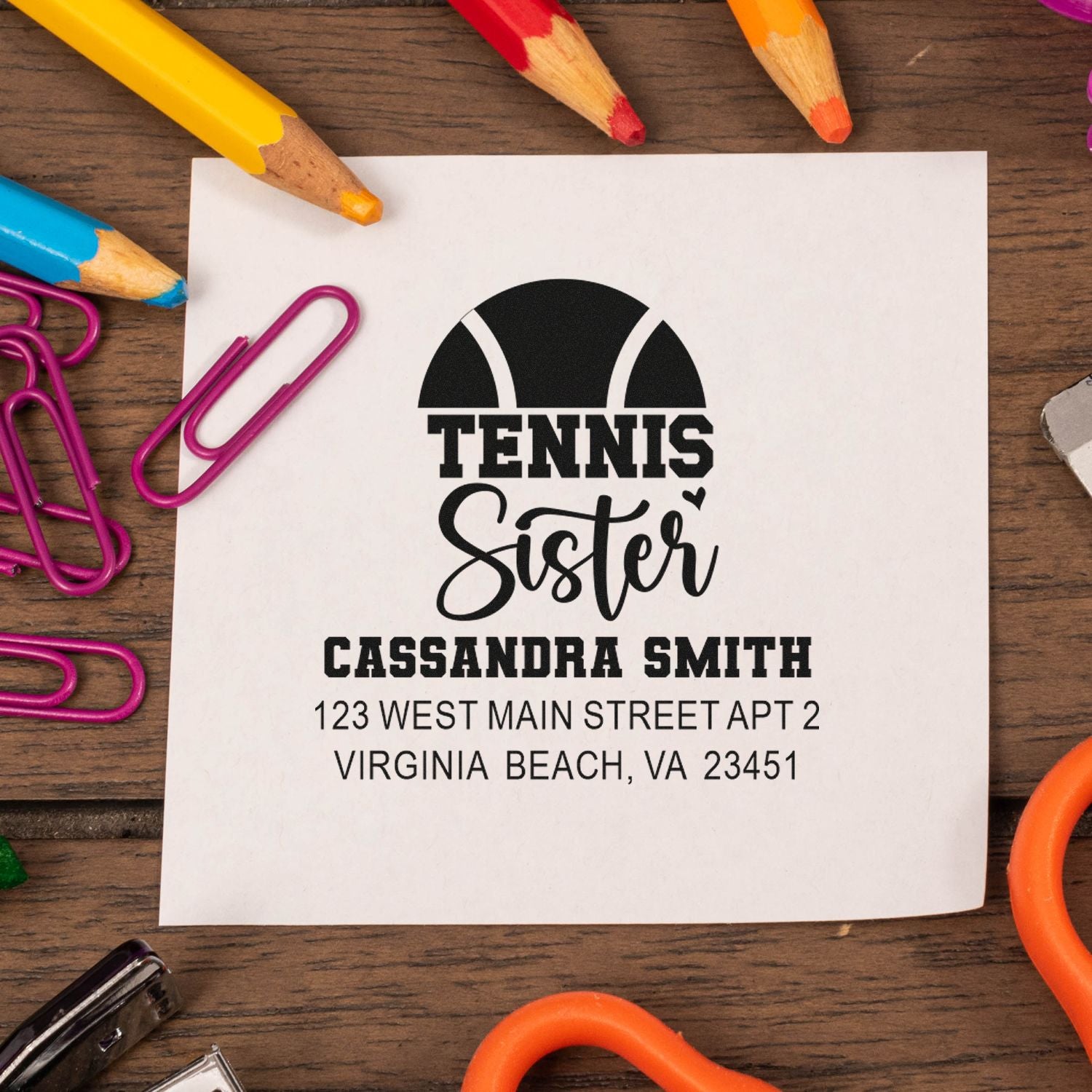 Personalized tennis sister address rubber stamp with name and mailing address, displayed on paper with colorful pencils.