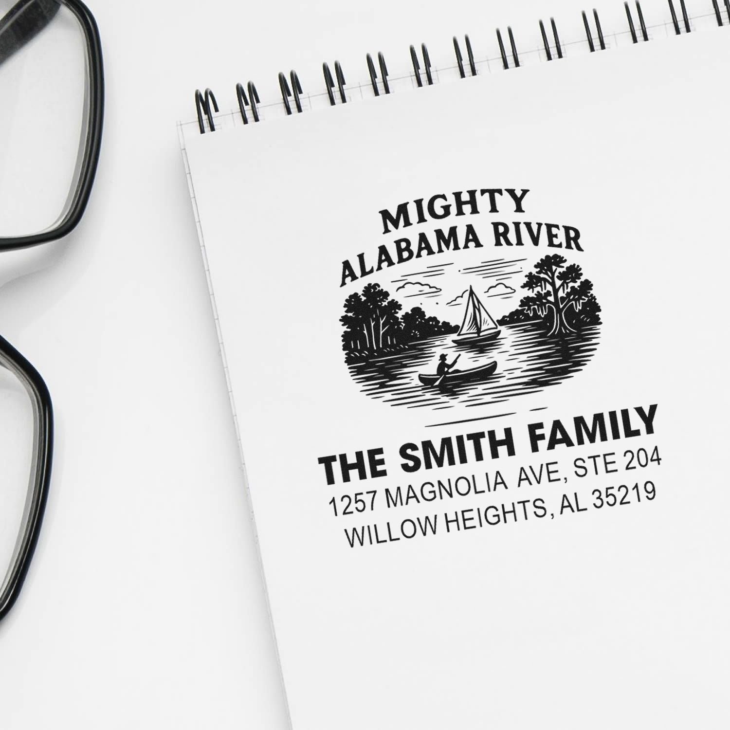 Custom rubber address stamp for the Smith family with Mighty Alabama River artwork and full return address on notebook.