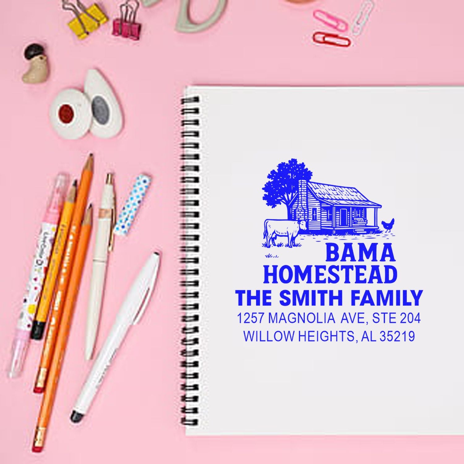 Custom homestead rubber stamp with farmhouse logo, family name, and address imprint on a notebook.