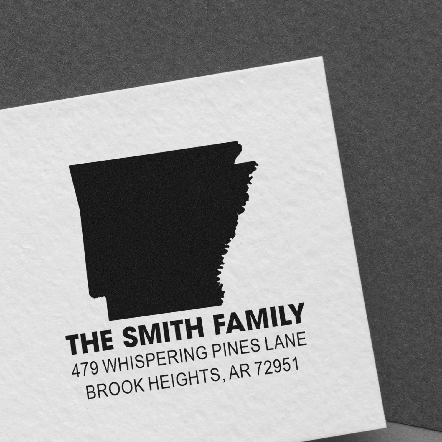 Personalized Arkansas return address rubber stamp for The Smith Family with state outline on white paper.