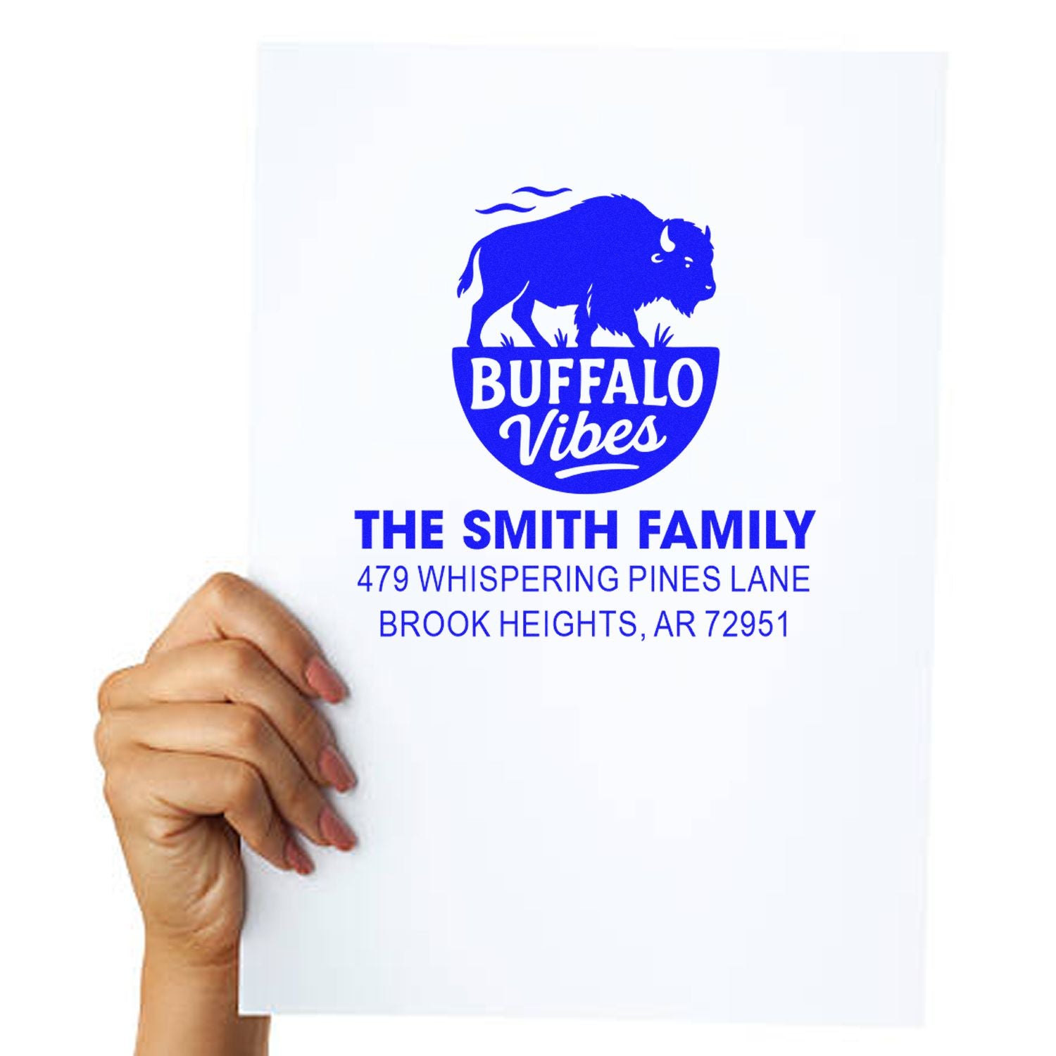 Hand holding a custom rubber stamp proof for The Smith Family with buffalo logo and address in Brook Heights, AR.