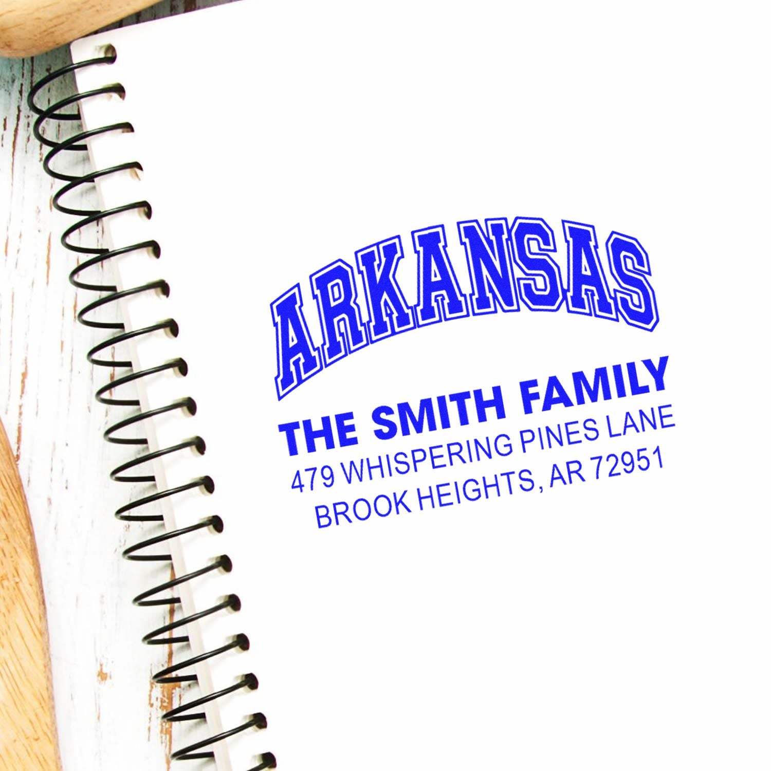 Custom Arkansas address rubber stamp for The Smith Family, with name and return address, shown on a notebook page.
