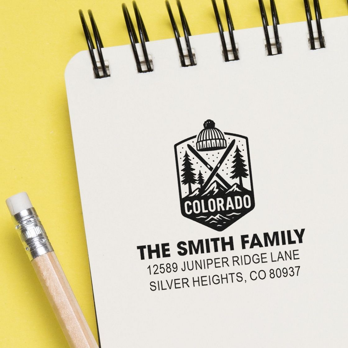 Custom family address rubber stamp on notebook, featuring a Colorado mountain emblem and personalized return address design.