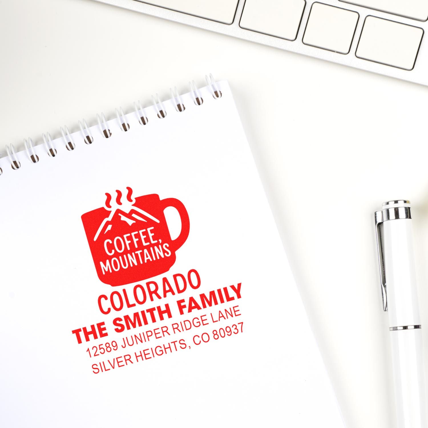 Custom return address rubber stamp impression with coffee mug logo and Colorado family address on notebook.