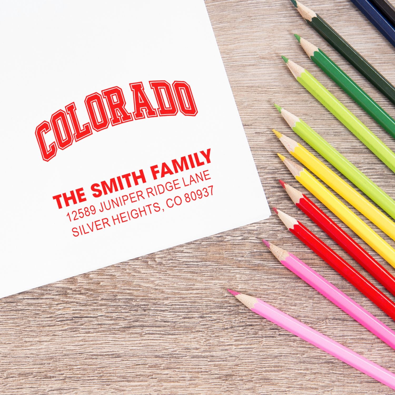Custom Colorado return address rubber stamp with family name imprint on paper beside colored pencils