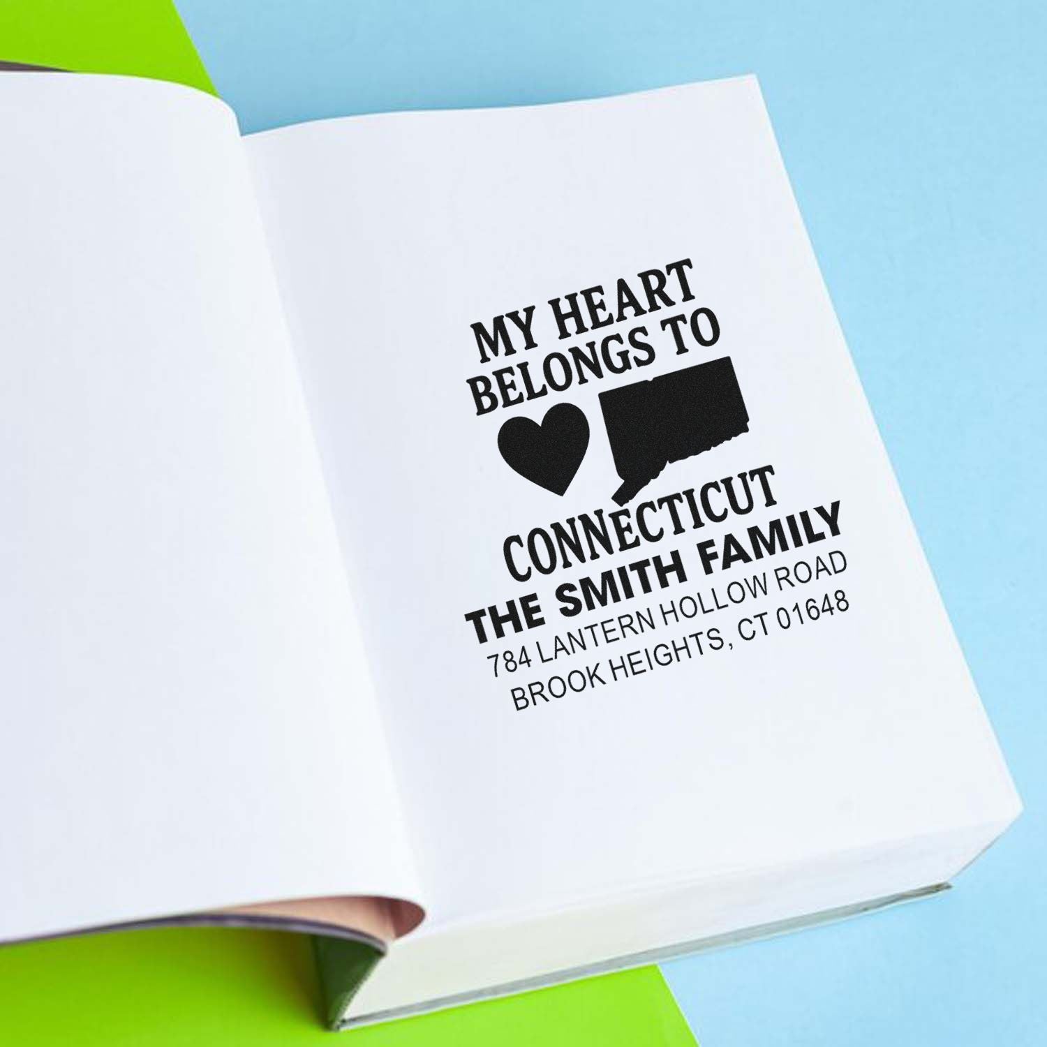 Custom rubber stamp imprint in a book, featuring a personalized family name and Connecticut return address for mailing.