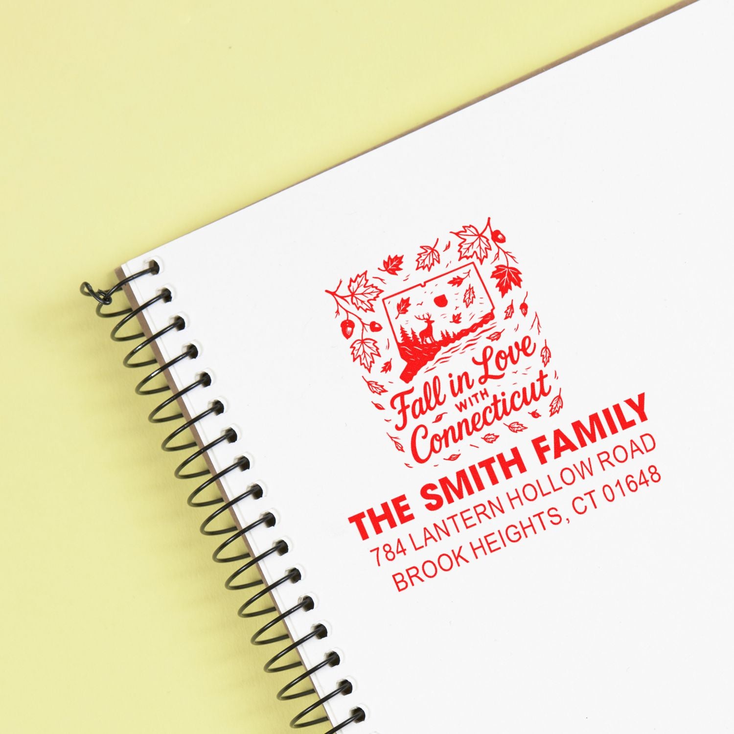 Custom rubber stamp on spiral notebook with fall-themed Connecticut design, family name, and address imprint.