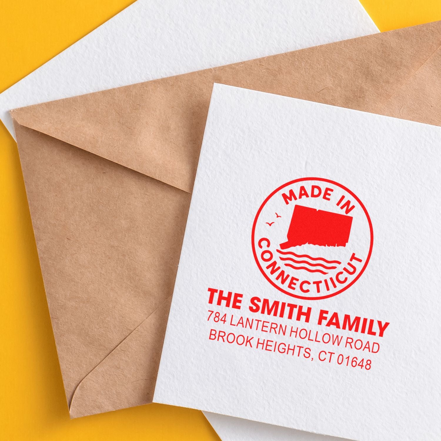 Custom return address rubber stamp on kraft and white envelopes, featuring a red Made in Connecticut family address design.