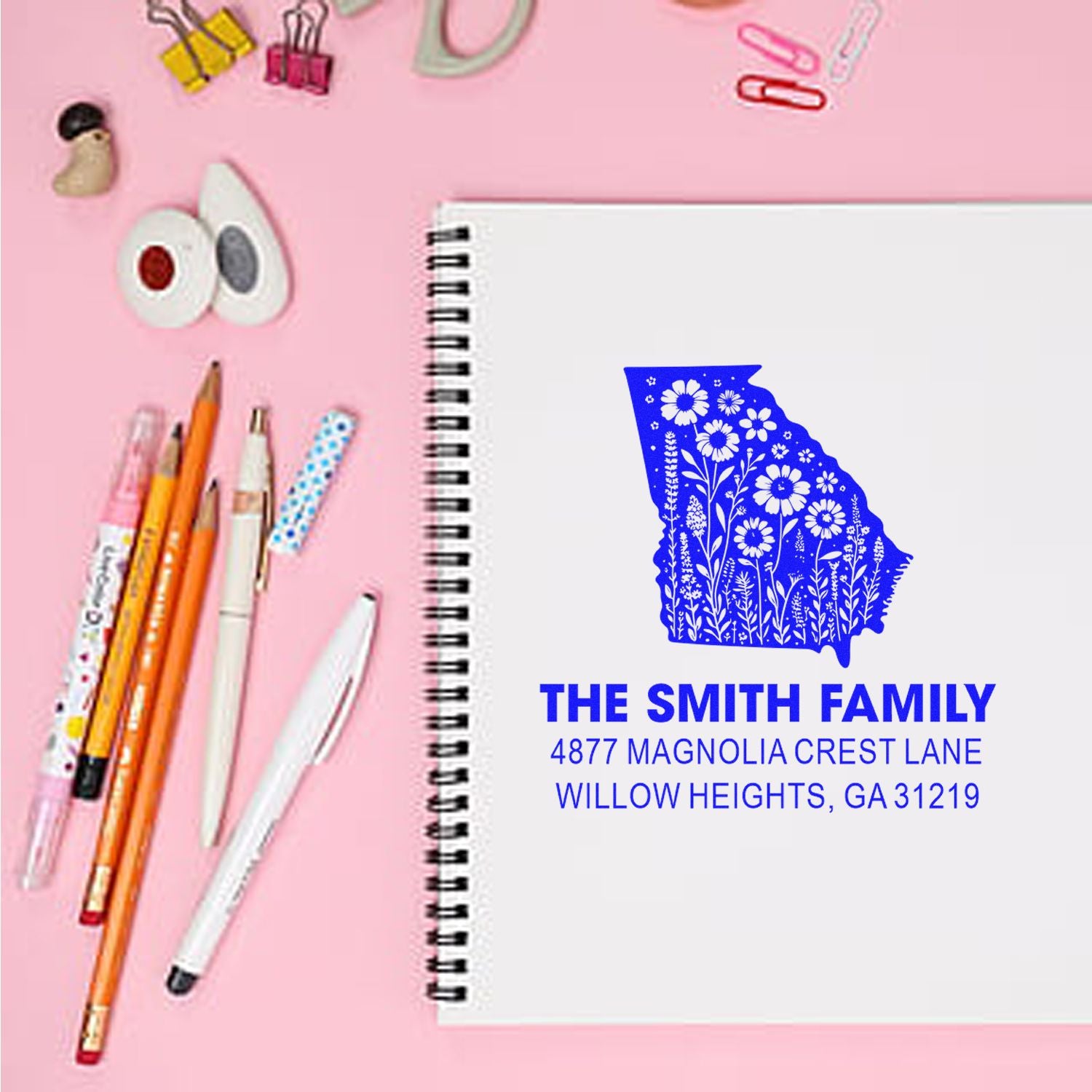 Custom return address rubber stamp with Georgia floral state design for The Smith Family, shown on a spiral notebook.